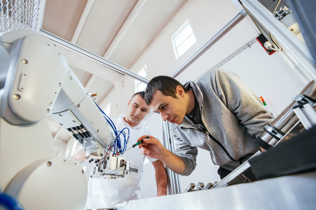 Engineers working on development of automated production line with robotic parts and applied software in order to increase productivity