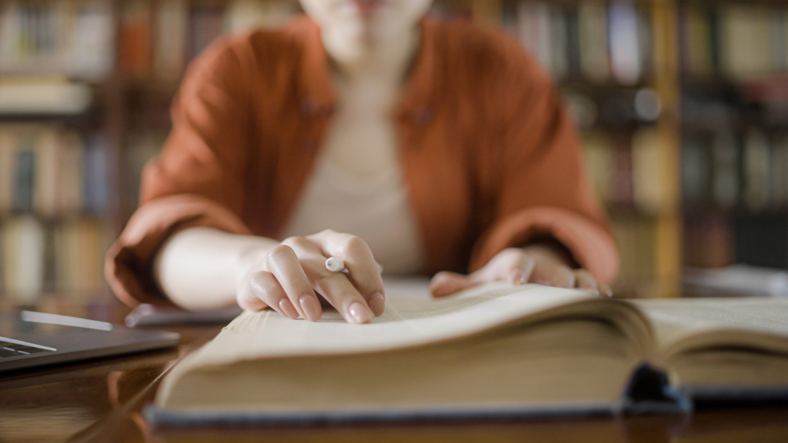 Eine Frau recherchiert in einer Bibliothek, indem sie ein Buch liest. Dies verdeutlicht, wie man über reine Schlagwörter hinausgeht und die semantische Vektorsuche nutzt, um Suchergebnisse relevanter und die Entdeckung neuer Informationen einfacher zu machen.